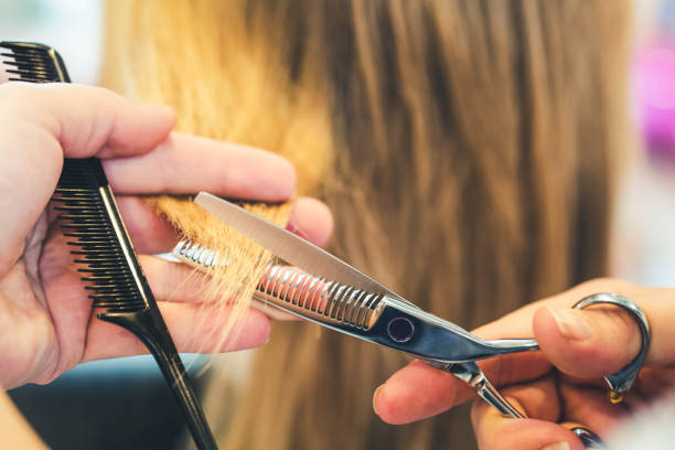 Close up hairstylist cutting hair in hair salon.